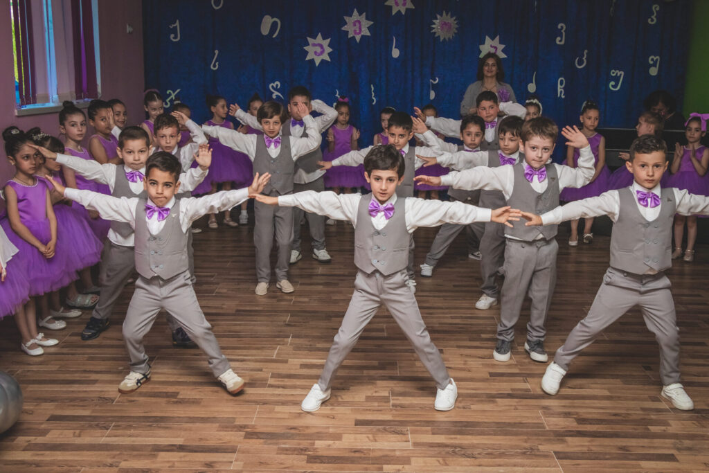 ბიჭები საცეკვაო ფორმებში იასამნისფერი პეპელა-ჰალსტუხებით.